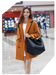 Detail of a large black leather tote bag paired with a stylish orange wool overcoat