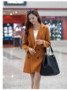 Detail of a large black leather tote bag paired with a camel wool coat in a modern mall