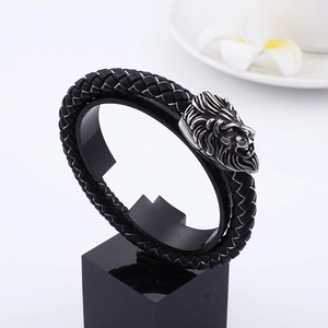 Men's leather braided bracelet with a detailed silver lion head buckle on a display stand