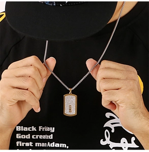 Close-up of rectangular gold and silver hip hop pendant with three cubic zirconia stones