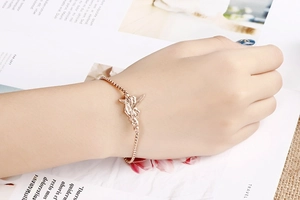 Detail of rose gold angel pendant bracelet on model wrist with adjustable sliding clasp