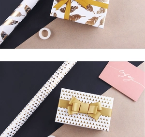 Detail of gold foil feather and geometric wrapping paper with satin ribbon for gifts