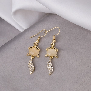 Detail of fox-shaped gold earrings with cat eye stone and sparkling crystals on silk