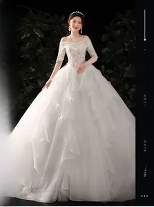 Detailed view of white off-shoulder bridal gown with lace embroidery and ruffled tulle skirt