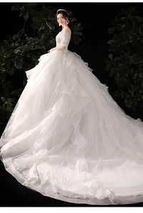 Detail of white off-shoulder bridal gown featuring tiered ruffle skirt and sequin bodice