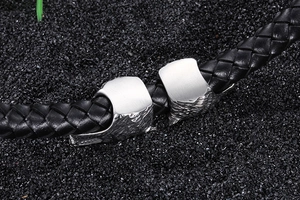 Close-up of black braided leather bracelet featuring vintage steel wolf head details