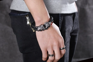 Detail of vintage braided leather bracelet with silver wolf heads and dark beads for men