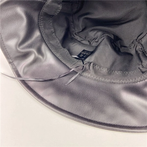 Interior details of a black faux leather bucket hat with adjustable drawstring and fabric lining