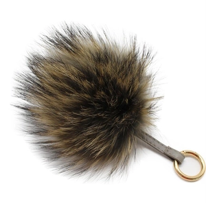 Détail d'un pompon en fourrure véritable avec lanière en cuir gris et anneau doré