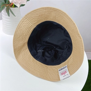 Fashionable tan flat-top bucket hat for women with unique brand label and adjustable strap