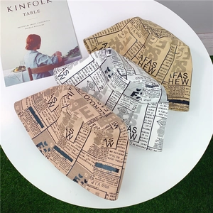 Three newspaper print bucket hats in white, beige and khaki colors on a white table