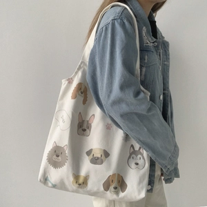 Side view of white canvas tote bag featuring cute cartoon dog illustrations on shoulder