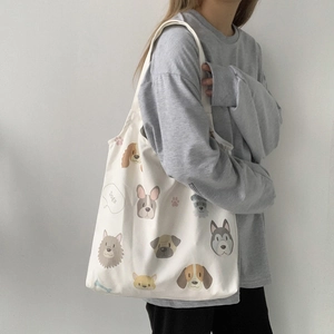 Detail view of cream canvas tote bag with dog illustrations shown on a model shoulder
