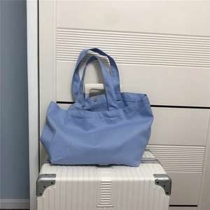 Detail van blauwe canvas draagtas met koperen metalen drukknoop op een koffer