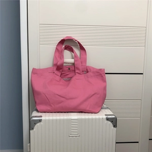 Detailopname van roze canvas shopper met brede hengsels en metalen drukknoopsluiting