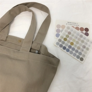 Detailopname van kaki canvas draagtas met twill textuur en metalen drukknoop sluiting
