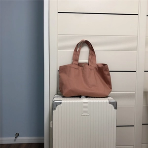 Detail van mauve canvas tote tas met metalen drukknoop op een witte koffer met textuur