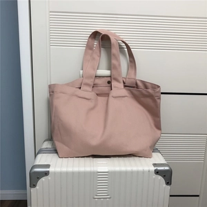 Detailweergave van de roze canvas shopper met metalen sluiting op een witte koffer