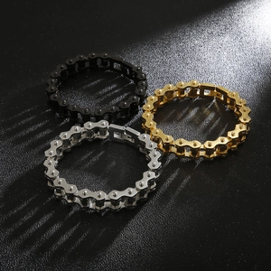 Three-color stainless steel bike chain bracelets in gold, silver and black on textured background