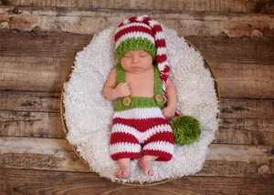 Detail of handmade knit Christmas newborn photo outfit with striped hat and suspender shorts