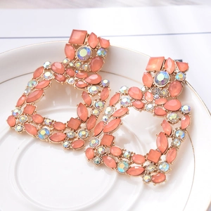 Detail of peach crystal stud earrings with gold geometric base and iridescent rhinestones