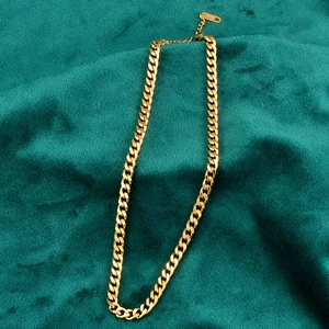 Polished gold thick curb chain necklace on green velvet background with extension