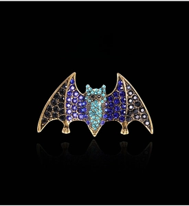 Detail of vintage bat brooch with blue rhinestones on a polished gold alloy base
