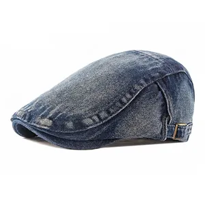 Coppola vintage in denim blu lavato con fibbia in metallo regolabile su sfondo bianco