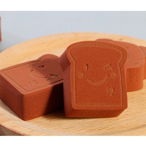 Close-up of toast-shaped brown makeup sponges with wink face on a wooden tray