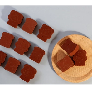 Macro shot of bear and toast shaped brown makeup sponges on a wooden tray and grey background