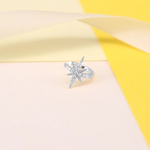 Detailed view of silver star ear cuff with zircon stones on silk ribbon background