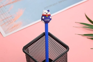 Close-up of a blue cartoon lucky cat pen featuring LUCKY text in a black desk organizer