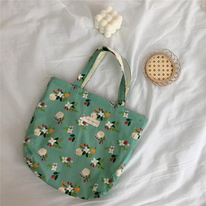 Close-up of floral cotton tote bag with green background and beige fabric label
