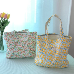 Detail of floral and lemon pattern cotton handbags on blue checkered tablecloth