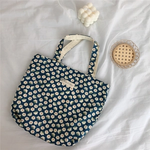 Detailed close-up of a blue floral cotton handbag with beige straps and daisy patterns