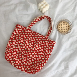 Detailed top view of red floral cotton handbag on a white fabric background