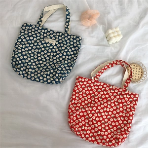 Flat lay detail of floral cotton tote bags in blue and red with daisy print patterns