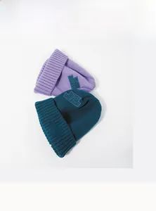 Close-up of purple and dark green knit beanies featuring detailed letter embroidery patches