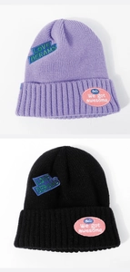 Detailed knit texture and embroidered letter patches on purple and black beanies
