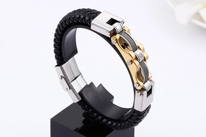 Detail of woven black leather bracelet with gold and silver mechanical links on display