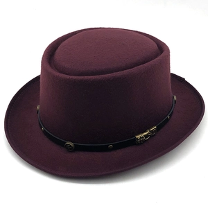 Dettaglio di un cappello in feltro bordeaux con fibbia vintage e fascia borchiata