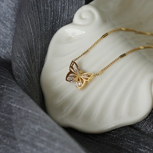 Detail shot of a butterfly pendant in gold titanium steel with cubic zirconia inlay