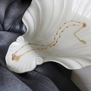 Macro detail of 18K gold-plated butterfly pendant with sparkling zircon stones on silk