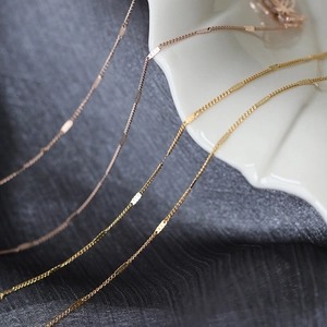 Macro detail of 18K gold plated titanium steel necklaces on elegant silk background