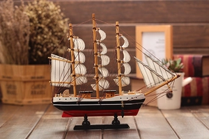Detailed close-up of a wooden sailboat model with white sails and vintage nautical rigging