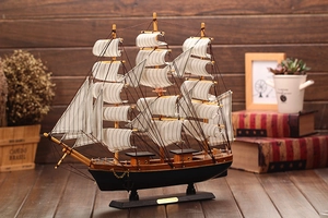 Close-up of vintage wooden sailboat model with white sails and golden Collection plaque
