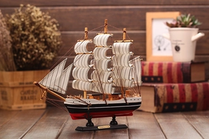 Detail of wooden Mediterranean sailing boat model with striped sails and decorative base