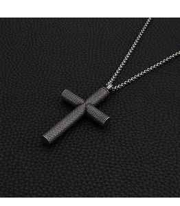Macro detail of silver cross pendant with textured grid finish on black leather background