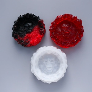 Three skull resin ashtrays in black-red, translucent red, and frosted white finishes
