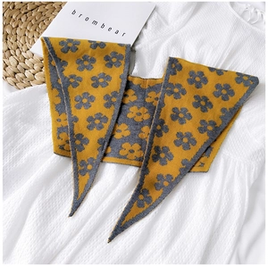 Detail of knitted shawl featuring yellow sunflower jacquard pattern on soft grey fabric
